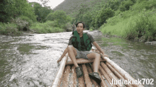 a man in a life vest is sitting on a bamboo raft in a river with judleklek702 written below him