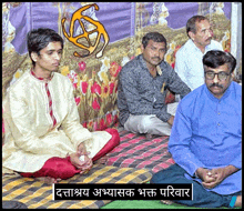 a group of men are sitting on a blanket with a sign in a foreign language that says ' a ' on it