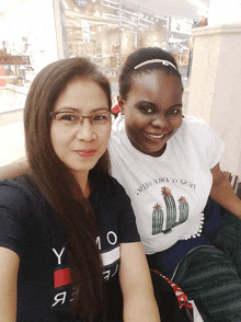 a woman wearing a tommy hilfiger shirt sits next to a woman wearing a cactus shirt