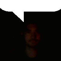 a man 's face is visible in the dark with a white speech bubble above it