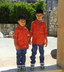 two young boys standing next to each other wearing red shirts