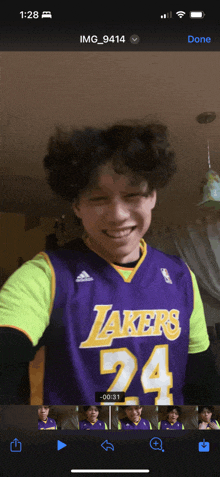 a young man wearing a purple lakers jersey is smiling