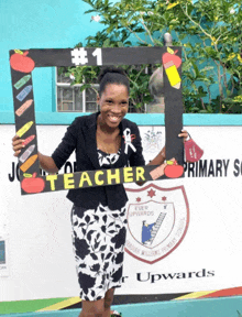 a woman holding a teacher sign in front of a school