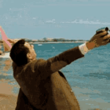 a man is taking a selfie on the beach with a camera