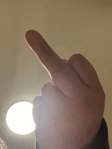 a person 's middle finger is pointing towards a light