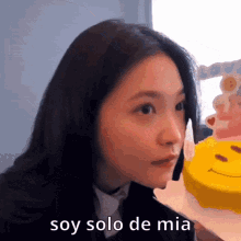 a girl is holding a yellow cake with a smiley face on it and the words soy solo de mia below her