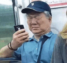 a man wearing a hat and glasses is looking at his cell phone on a bus .