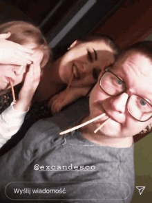 a man with glasses and straws in his mouth is surrounded by two girls