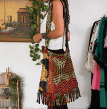 a woman wearing a colorful purse stands in front of a picture