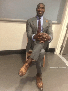 a man in a suit sits with his legs crossed