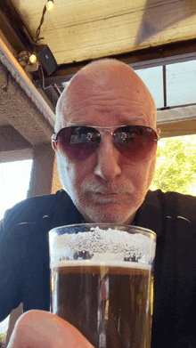 a man wearing sunglasses and holding a glass of beer