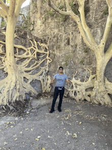 a man wearing a t-shirt that says california stands in front of a large tree