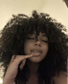 a woman with curly hair and braces on her teeth is taking a picture of herself .