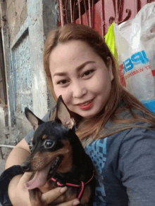 a woman is holding a small dog in front of a bag that says pepsi