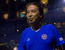 a man wearing a blue adidas shirt with a soccer ball on the front