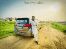 a man in a turban stands next to a car that says not available