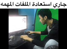 a man sits at a desk in front of a computer screen with arabic writing on it