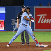 a baseball player in a blue jays uniform stands in front of an advertisement for tim hortons