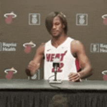 a man in a heat jersey is sitting at a table with a microphone