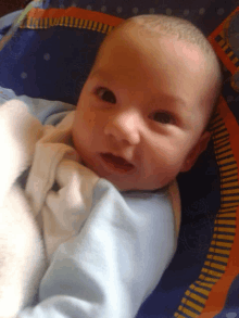 a baby is laying on a blue and orange blanket and smiling