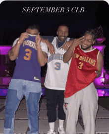 three men are posing for a picture and one of them has the number 3 on his shirt