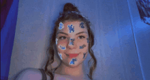 a girl with stickers on her face looks at the camera .