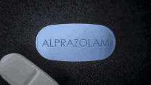 a blue alprazolam pill is sitting on a black surface