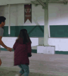 a man and a woman are holding hands in a room with a banner on the wall that says ' athletics '