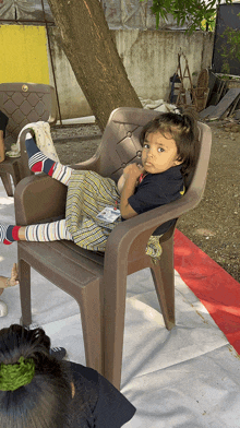 a little girl sits in a chair with her feet up