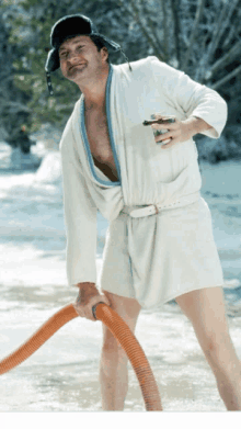 a man in a bathrobe and hat is holding a hose