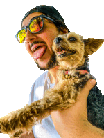 a man wearing sunglasses is holding a small dog in his arms