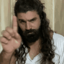 a man with long hair and a beard is pointing his finger up