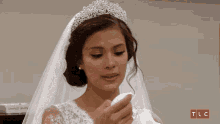 a woman in a wedding dress is crying with a tissue in her hand