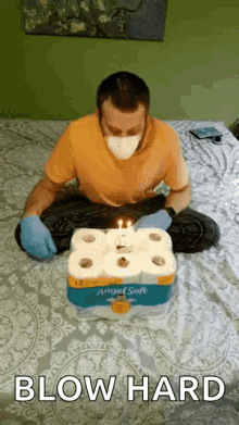 a man wearing a mask and gloves is blowing out candles on a birthday cake made out of toilet paper