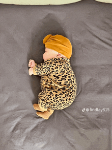 a baby wearing a leopard print outfit and a turban sleeping on a bed