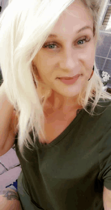 a blonde woman wearing a green shirt is smiling for the camera