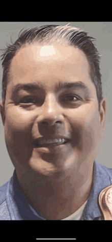 a close up of a man 's face with a blue shirt on smiling .