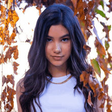 a woman with long dark hair is wearing a white tank top