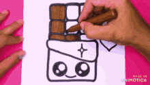 a person is drawing a chocolate bar with a face on a piece of paper