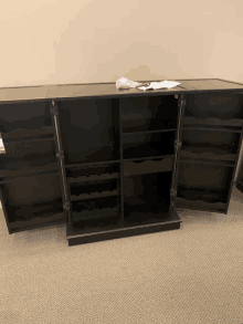 a wooden cabinet with the doors open and wine bottles on the shelves