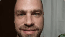 a close up of a man 's face with blue eyes and a beard