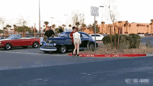 a woman stands in front of a car in a parking lot with a no parking sign in the background