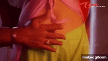 a man is touching a woman 's stomach in a pink shirt and green skirt .