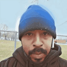 a man with a beard wearing a blue beanie and a hoodie