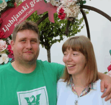 a man and a woman are posing in front of a sign that says ljubljanski grad