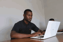 a man in a black shirt is typing on a white asus laptop