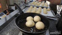 a bunch of doughnuts are being cooked in a frying pan with the words made in animotica on the bottom