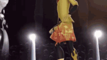 a woman in a yellow jacket and orange skirt is dancing on a stage