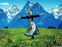 a woman is dancing in a field with mountains in the background and the website memeful.com is below her