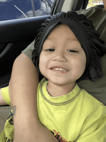 a little boy wearing a black hat and a yellow shirt smiles